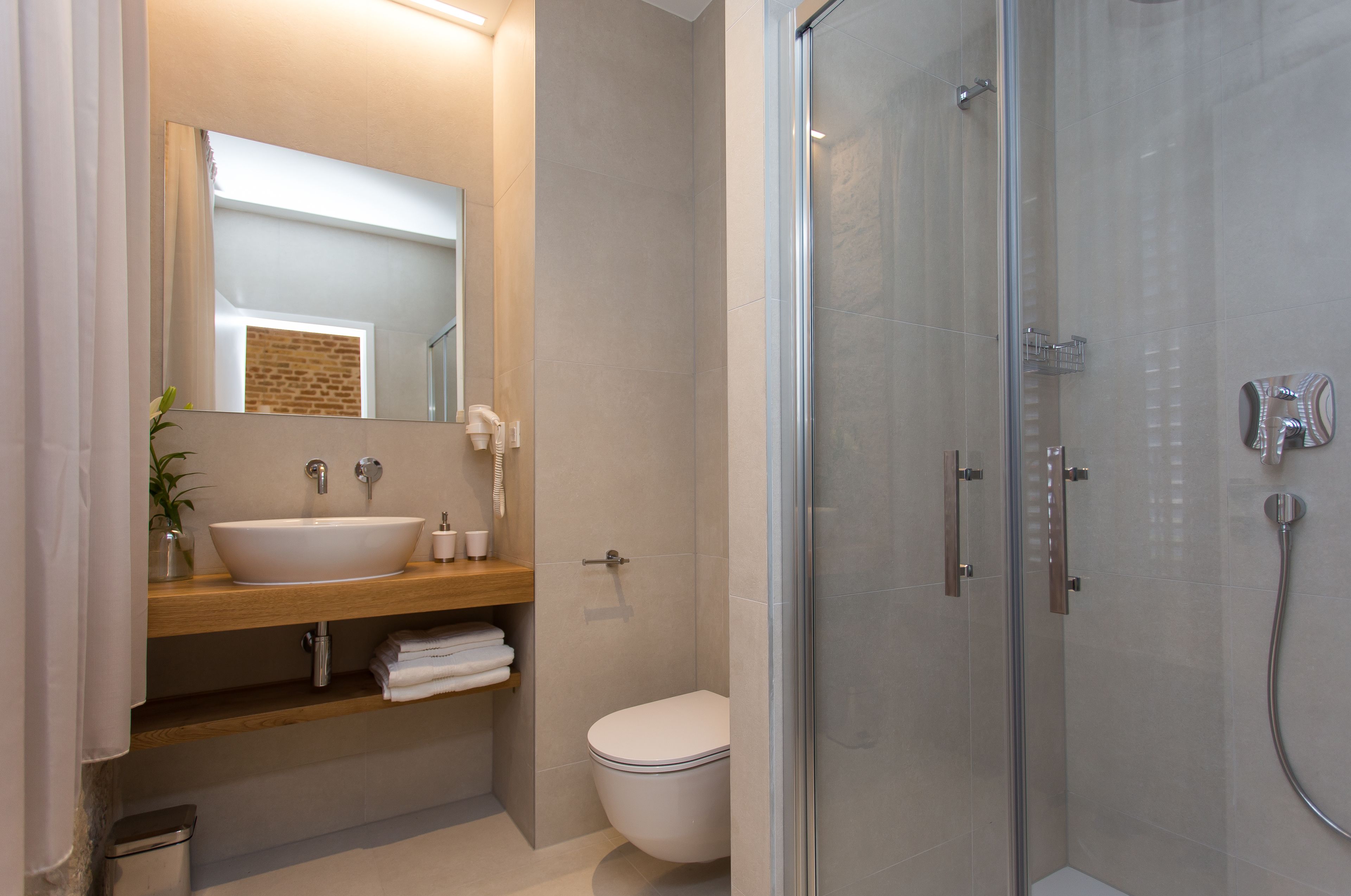 A modern bathroom with a glass shower enclosure, a white sink, and a visible toilet.