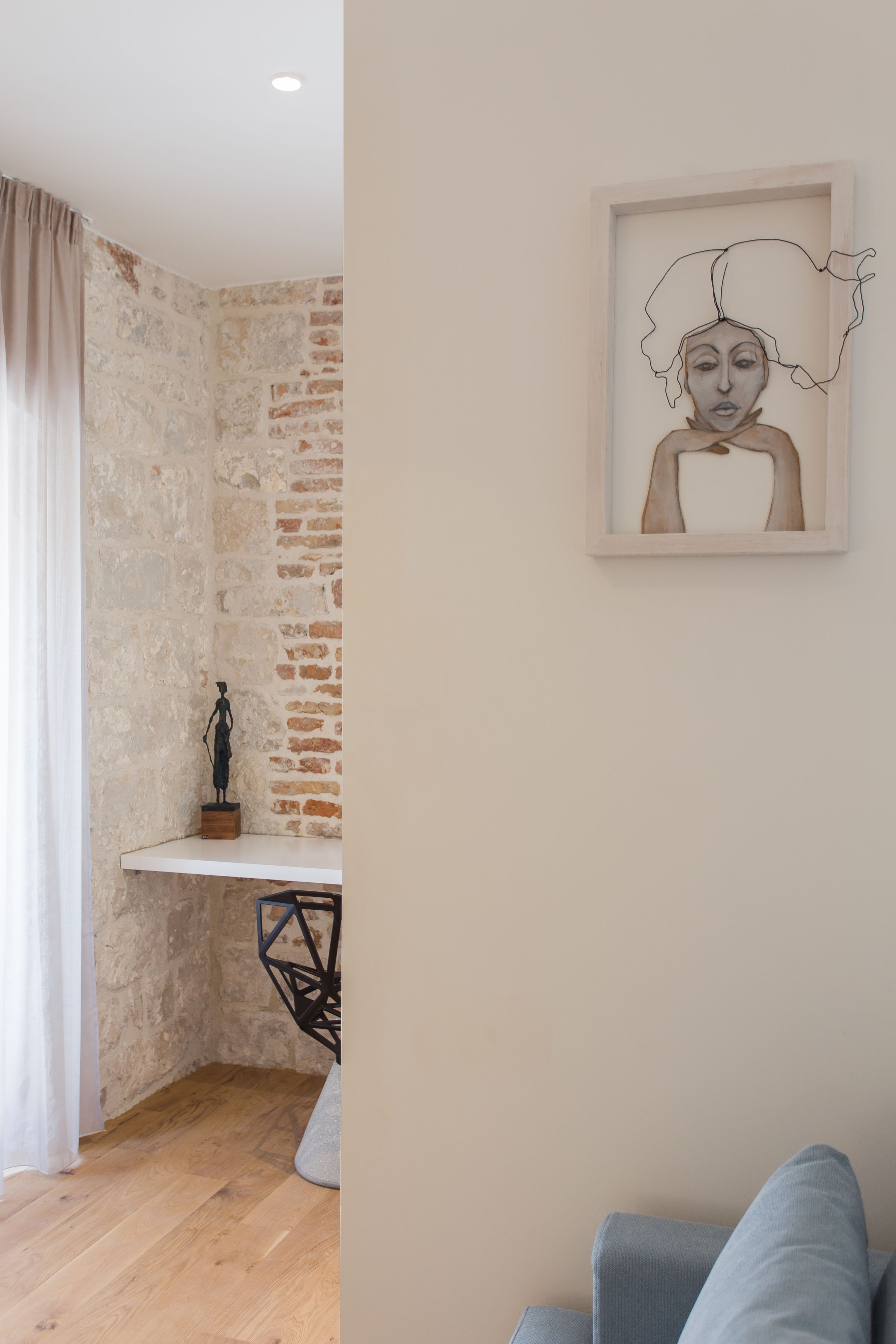 Ein Zimmer mit einer Steinsäule, einem kleinen Tisch mit einer Statue und einem gerahmten Kunstwerk an der Wand.