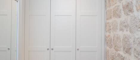 Un armario blanco con dos puertas y una pared de piedra.