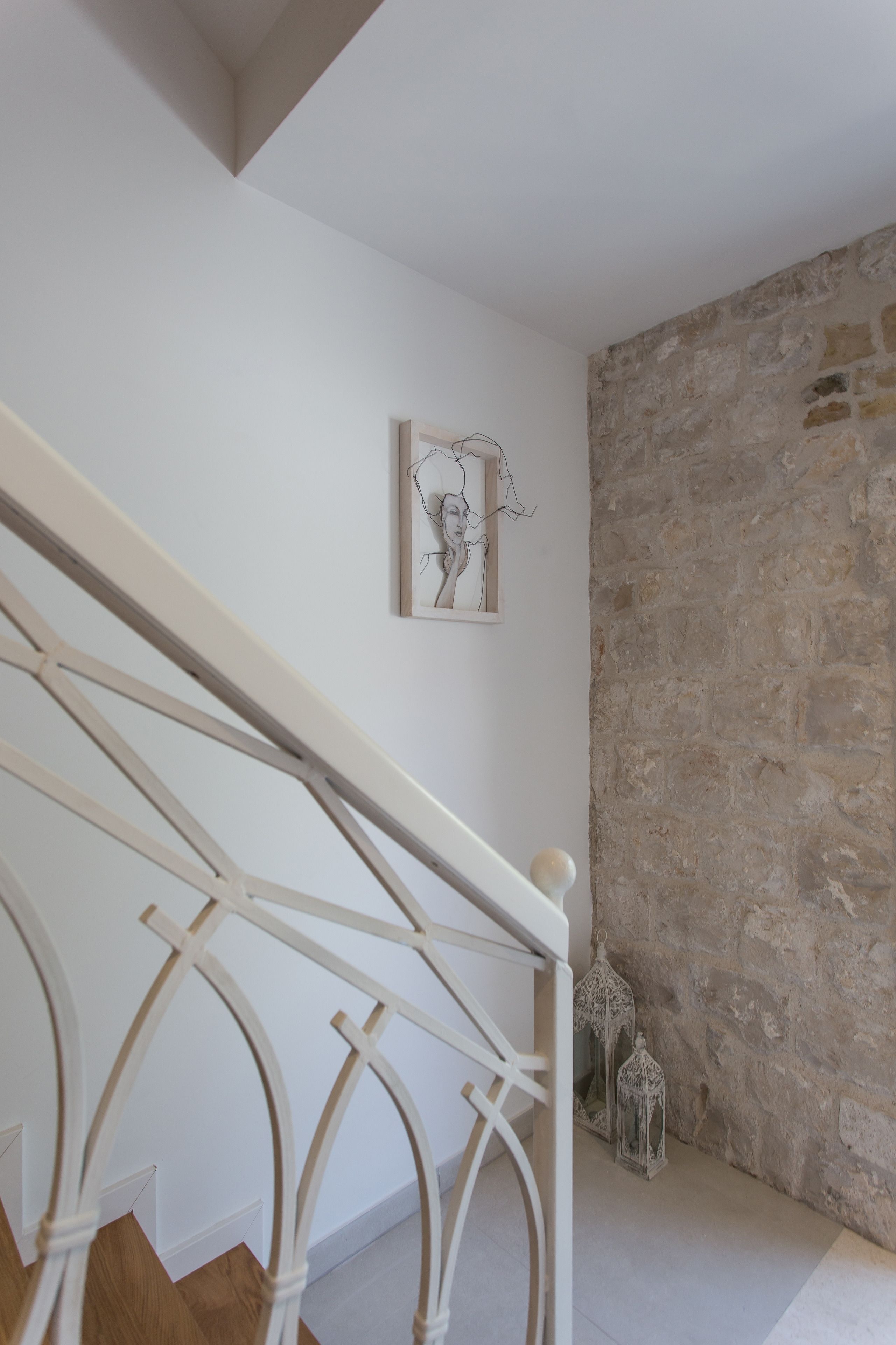 A staircase with a white railing and a stone wall.