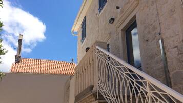 A stone building with a tiled roof, a white railing, and a clear blue sky.