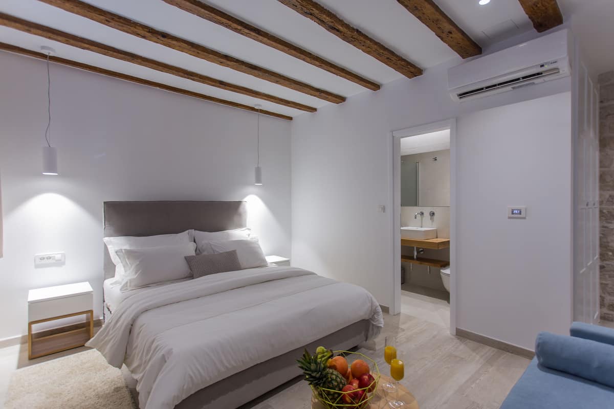 A modern bedroom with a bed, bedside table, and a fruit basket.