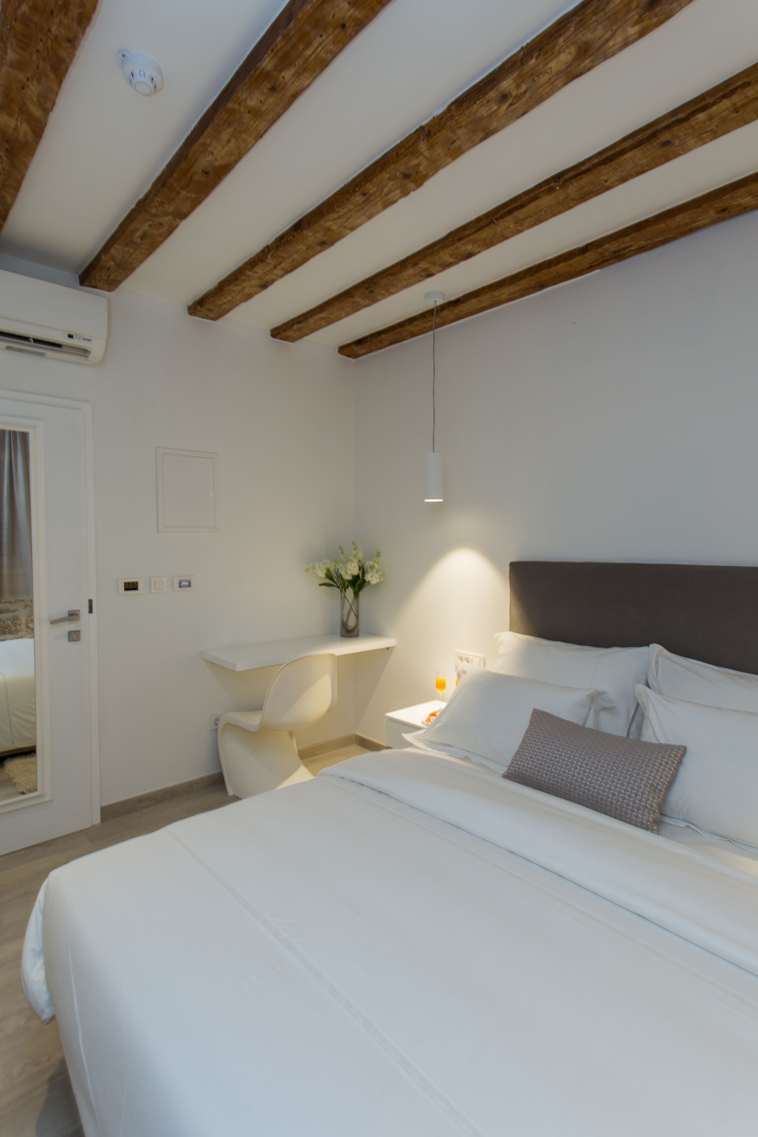Ein Schlafzimmer mit einem Bett, einem Nachttisch und einer Wand-Klimaanlage.