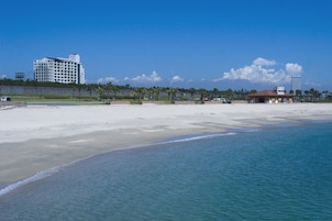 A beach with a hotel and a building in the background.