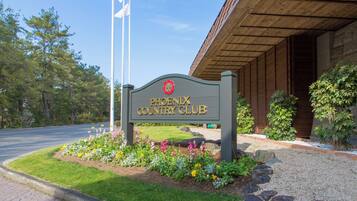 A sign for the Phoenix Country Club with a landscaped garden in front.