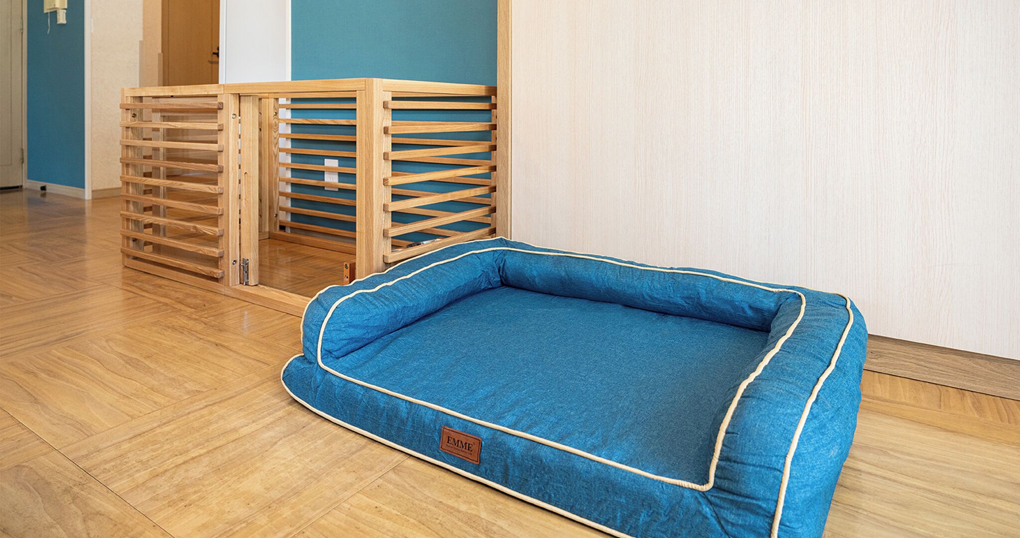 A blue pet bed with a wooden crate structure in the background.