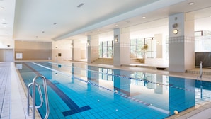 A large indoor swimming pool with clear lanes, a lifeguard chair, and a tiled floor.