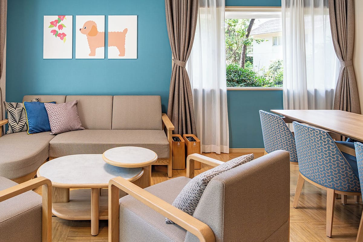 A modern living room with a sectional sofa, a round coffee table, and a dining area with patterned chairs.