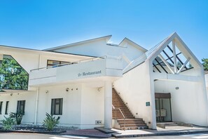 A modern building with a flat roof, a staircase leading to a second floor, and a sign indicating it is a restaurant. - Seagaia Forest Cottages (Miyazaki)