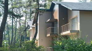 A modern two-story building with balconies, surrounded by dense forest. - Seagaia Forest Cottages (Miyazaki)