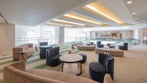 A spacious lobby with modern furniture, a staircase, and a glass railing.