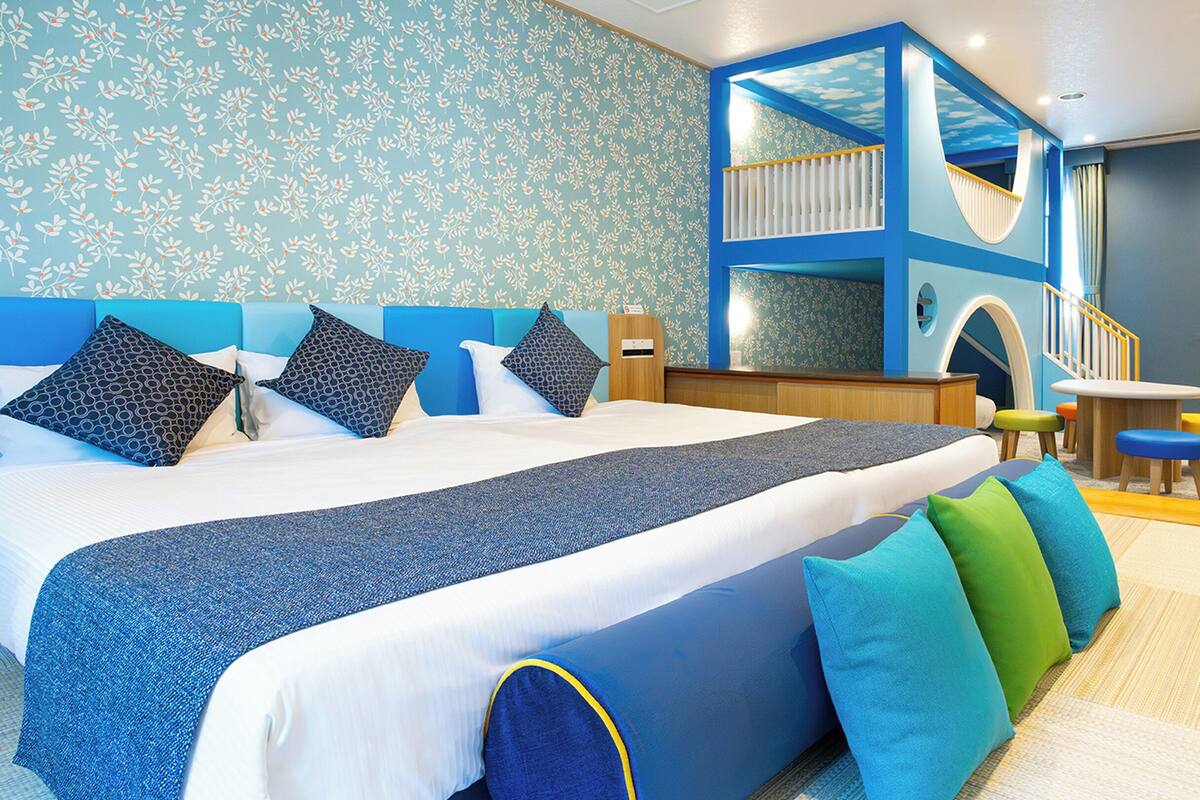 A hotel room with a large bed, a play area, and a staircase.