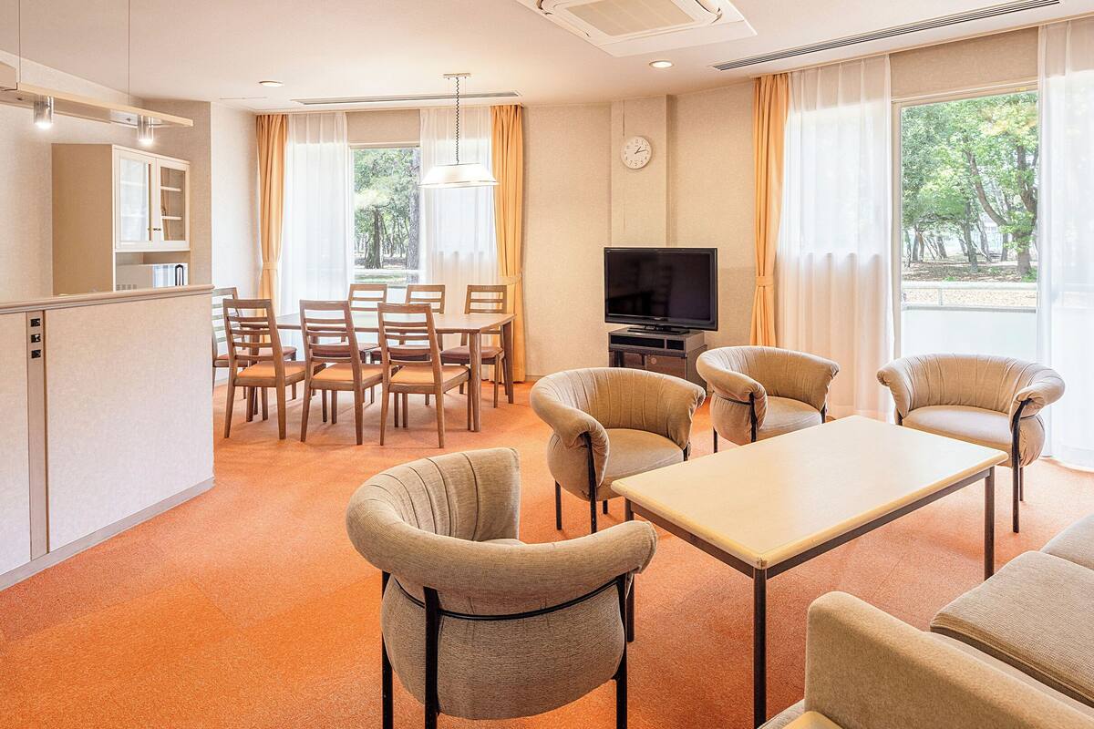 A hotel room with a dining area, a TV, and a sofa.