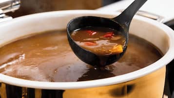 A ladle lifting soup from a pot.