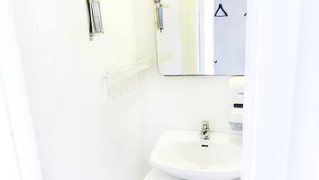 Ein Badezimmer mit weißem Waschbecken, Spiegel und Schrank.