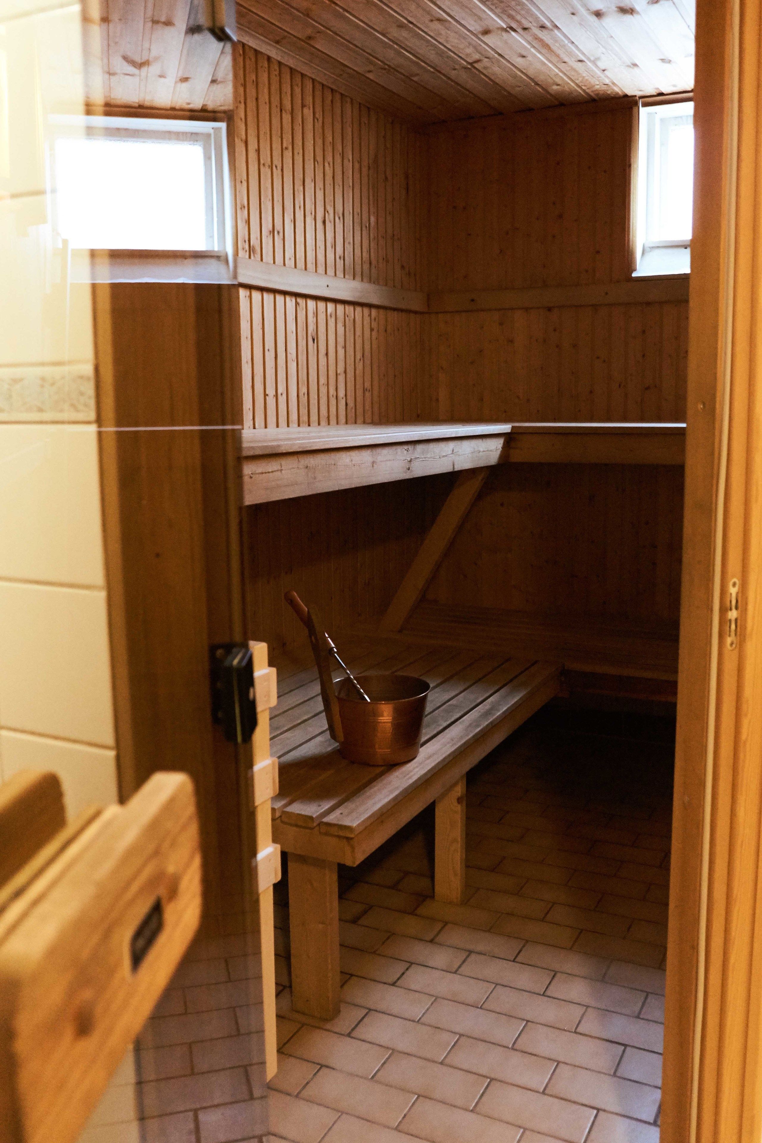 Un sauna en bois, avec des bancs et un seau en cuivre.