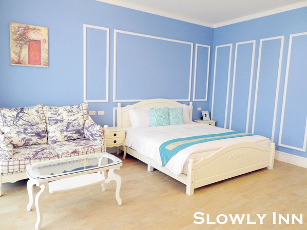 A bedroom with a bed, a sofa, a glass coffee table, and a nightstand. - Slowly Inn (Hengchun)