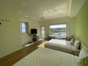 A hotel room with two beds, a TV, a small table, and a balcony with a view of the countryside. - Slowly Inn (Hengchun)