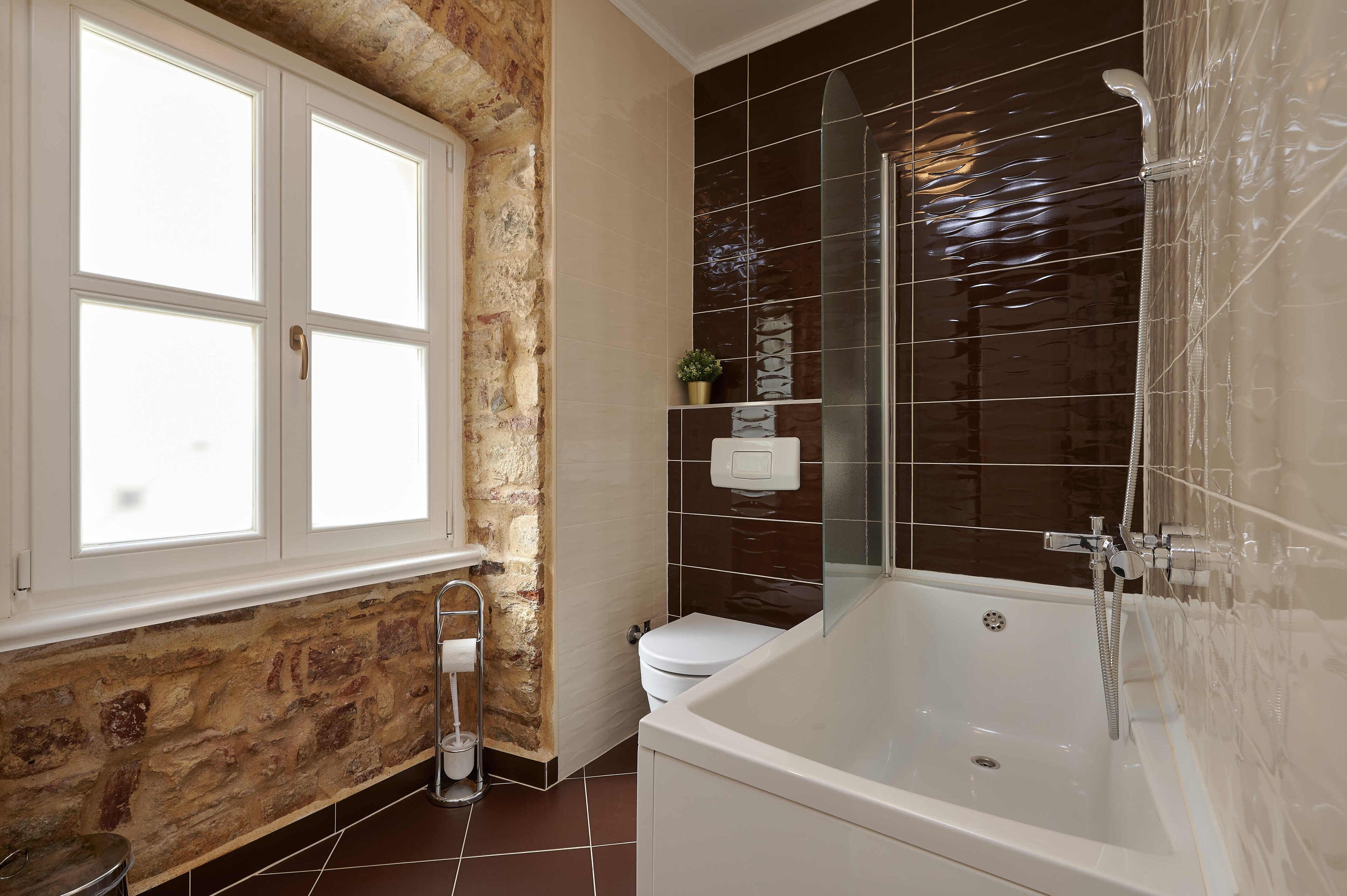A bathroom with a bathtub, toilet, and a window.