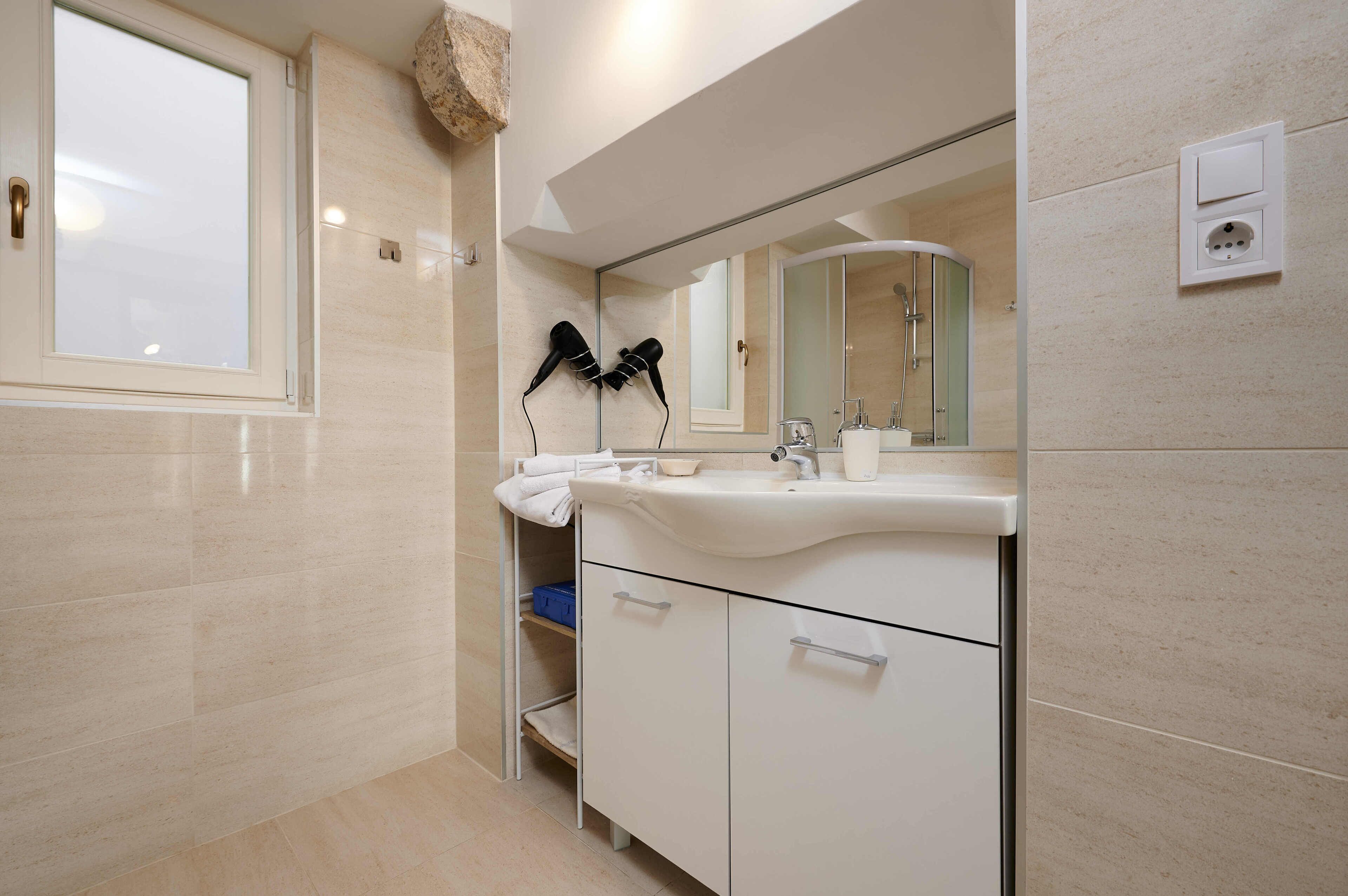 A modern bathroom with a large mirror, a white sink, and a towel rack.