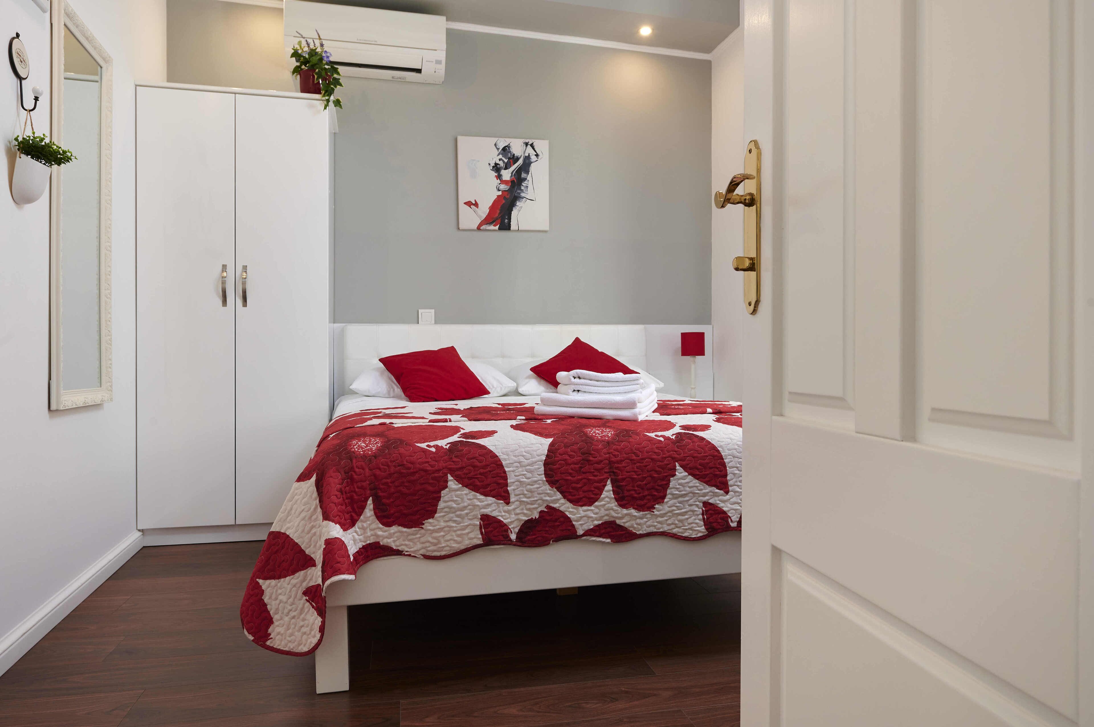 Un dormitorio con cama, armario blanco y un cuadro en la pared.