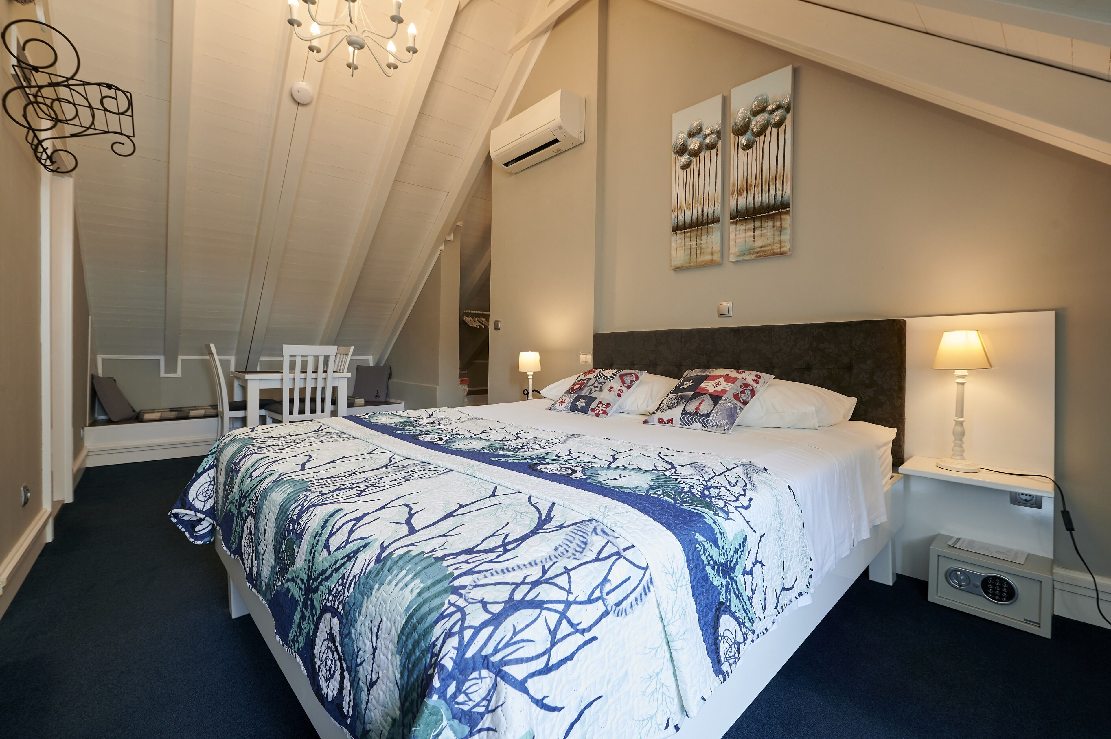 A bedroom with a large bed, a nightstand with a lamp, a chair, and a ceiling fan.