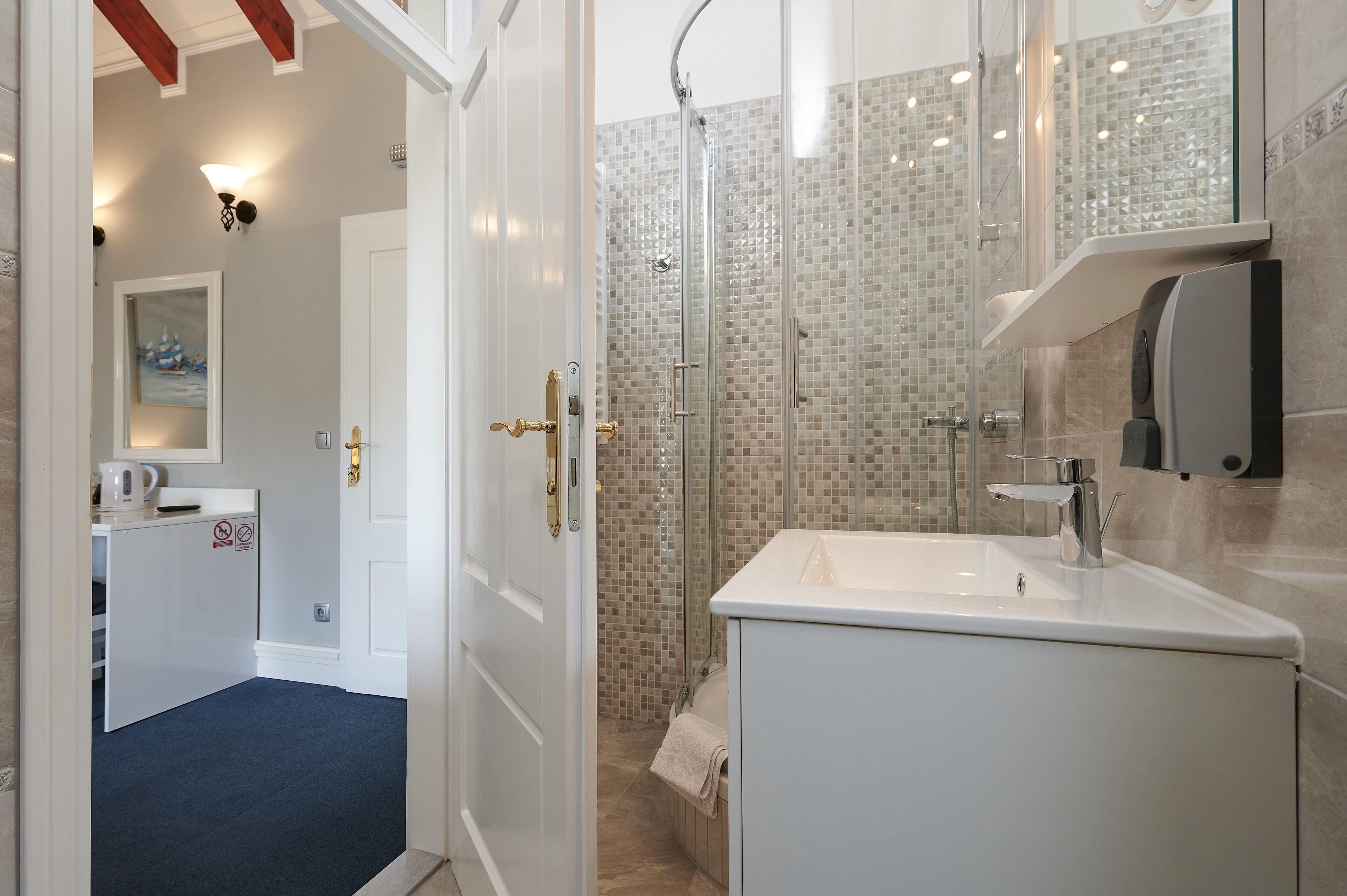 Een moderne badkamer met een douchecabine van glas, een witte wastafel en een handdoekhouder.