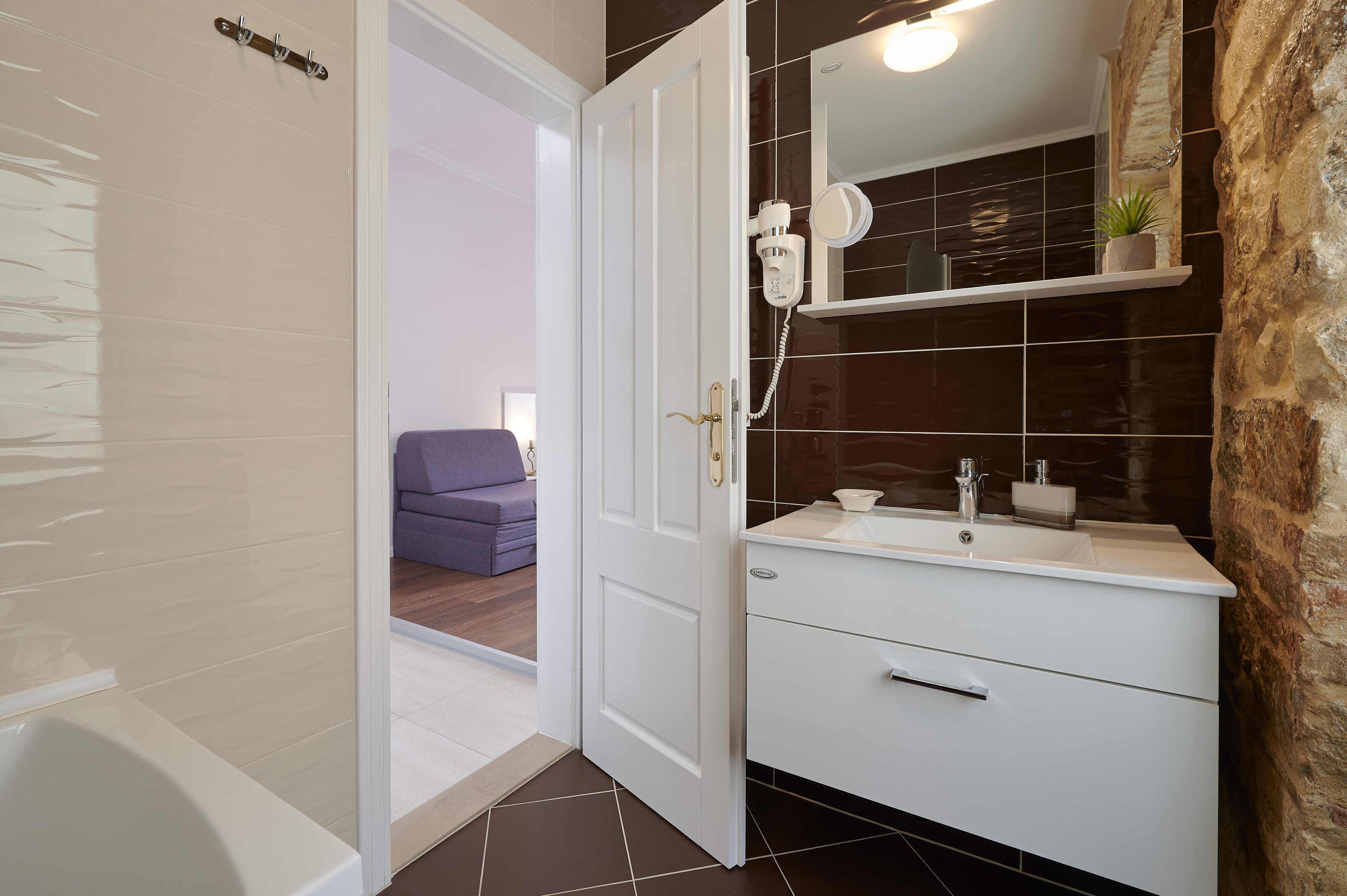 Une salle de bain avec un meuble-lavabo blanc, un miroir, un sèche-cheveux et un porte-serviettes.