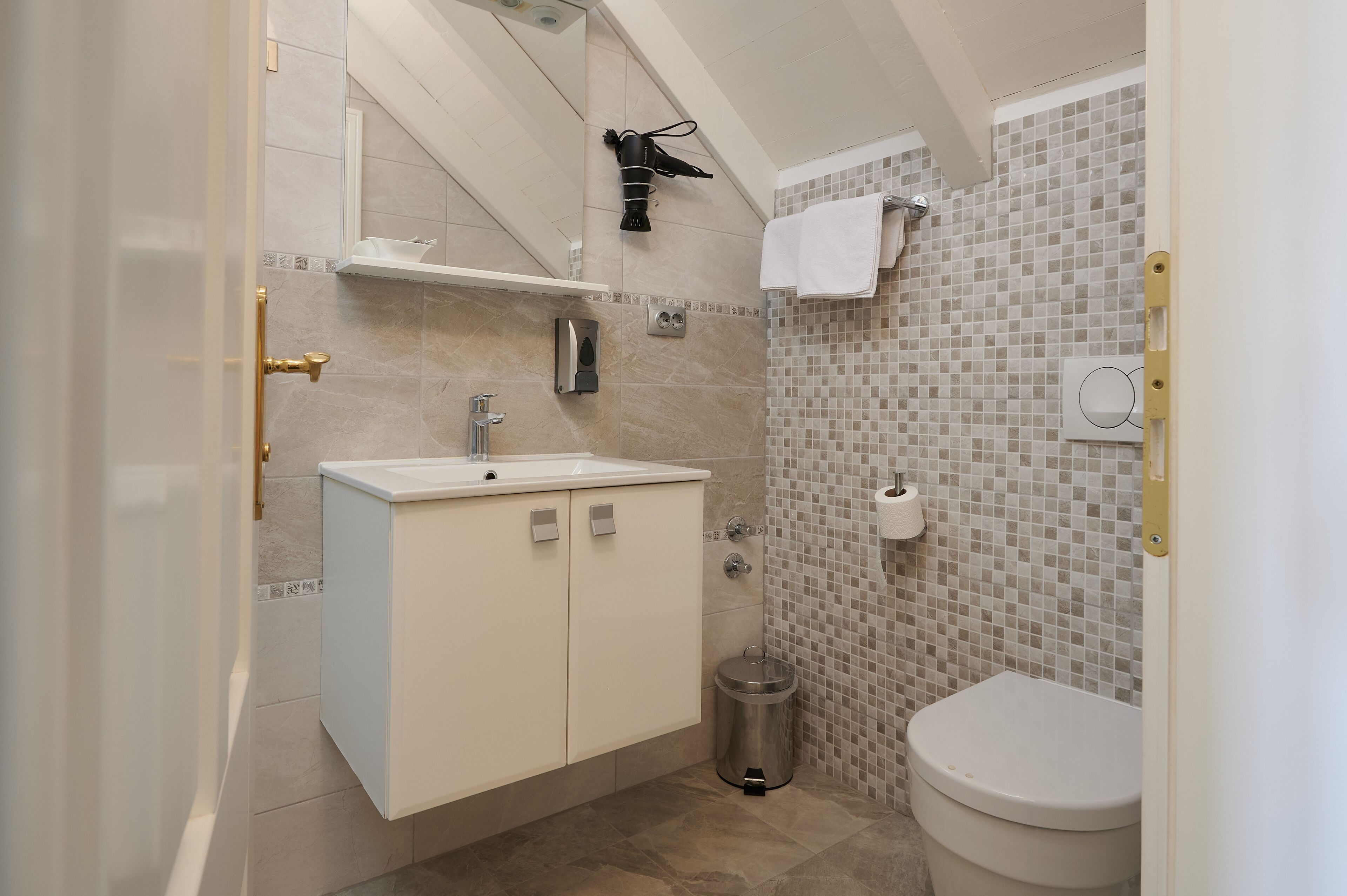 Un baño con lavamanos, espejo, toallero y retrete.