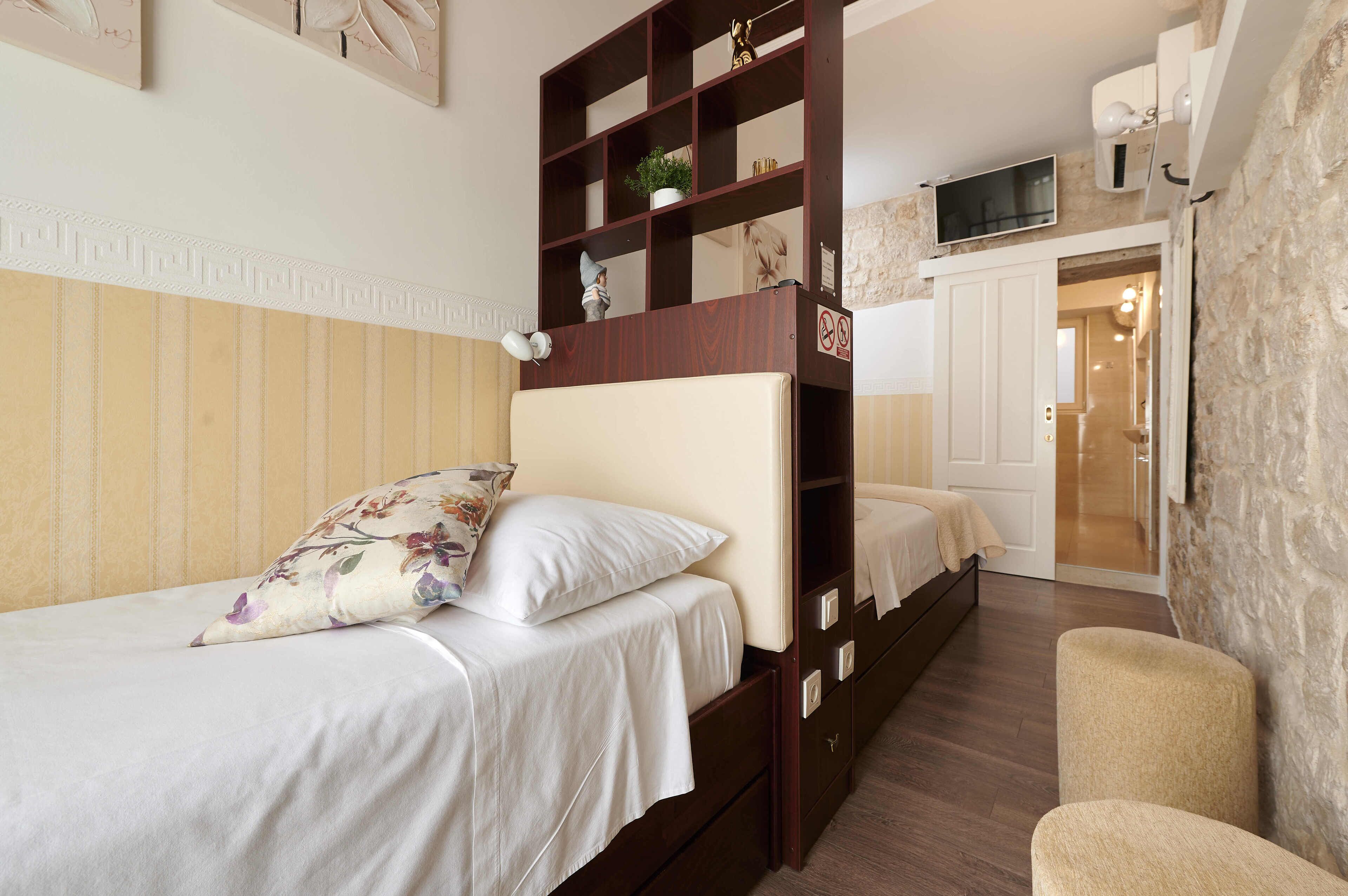Un dormitorio con literas, una mesita de noche, una silla y un televisor montado en la pared.