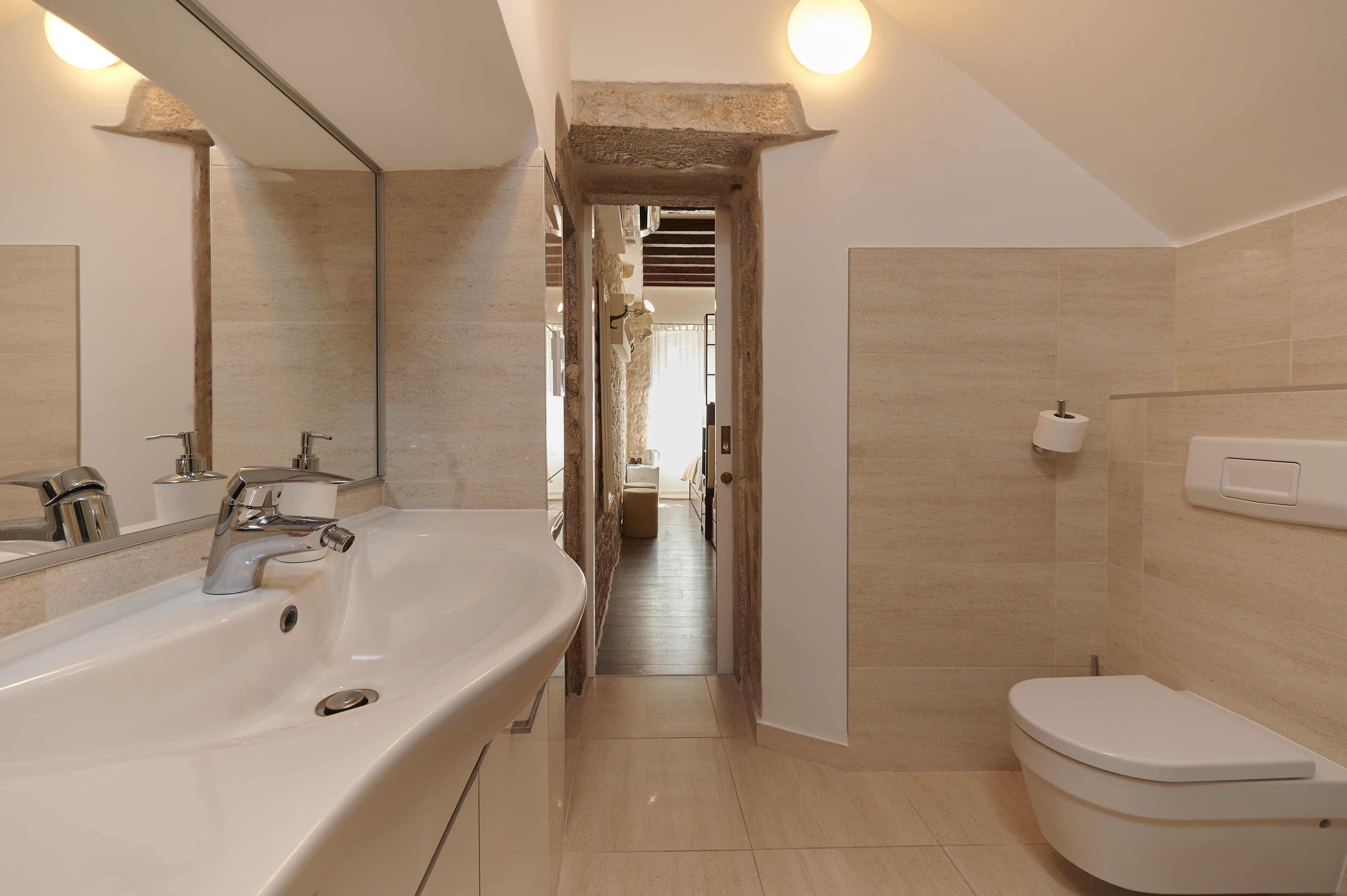 A modern bathroom with a large sink, a toilet, and a mirror.
