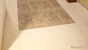 A hallway with a patterned carpet, wooden doors, and a ceiling light. - M Suites Hotel (Makati)