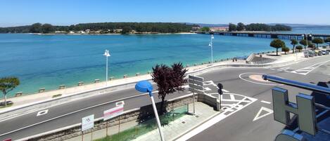 Una carretera costera con vista despejada al mar y un puente a lo lejos.