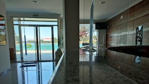 A modern lobby with a glass door leading outside, a marble reception desk, and a view of the outdoors. - Hotel Brisa del Mar (O Grove)