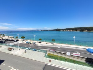 Una carretera costera con vista despejada al mar, un área de estacionamiento y una senda peatonal.
