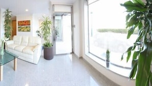 A modern hotel lobby with a glass coffee table, a sofa, and several potted plants. - Hotel Brisa del Mar (O Grove)