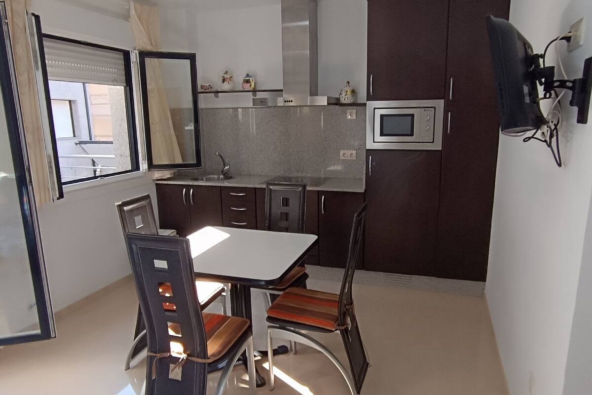 A compact kitchen with a dining table and chairs, a microwave, and cabinets.