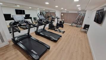 Une salle de sport équipée de tapis de course, de vélos d’appartement et d’appareils de musculation.