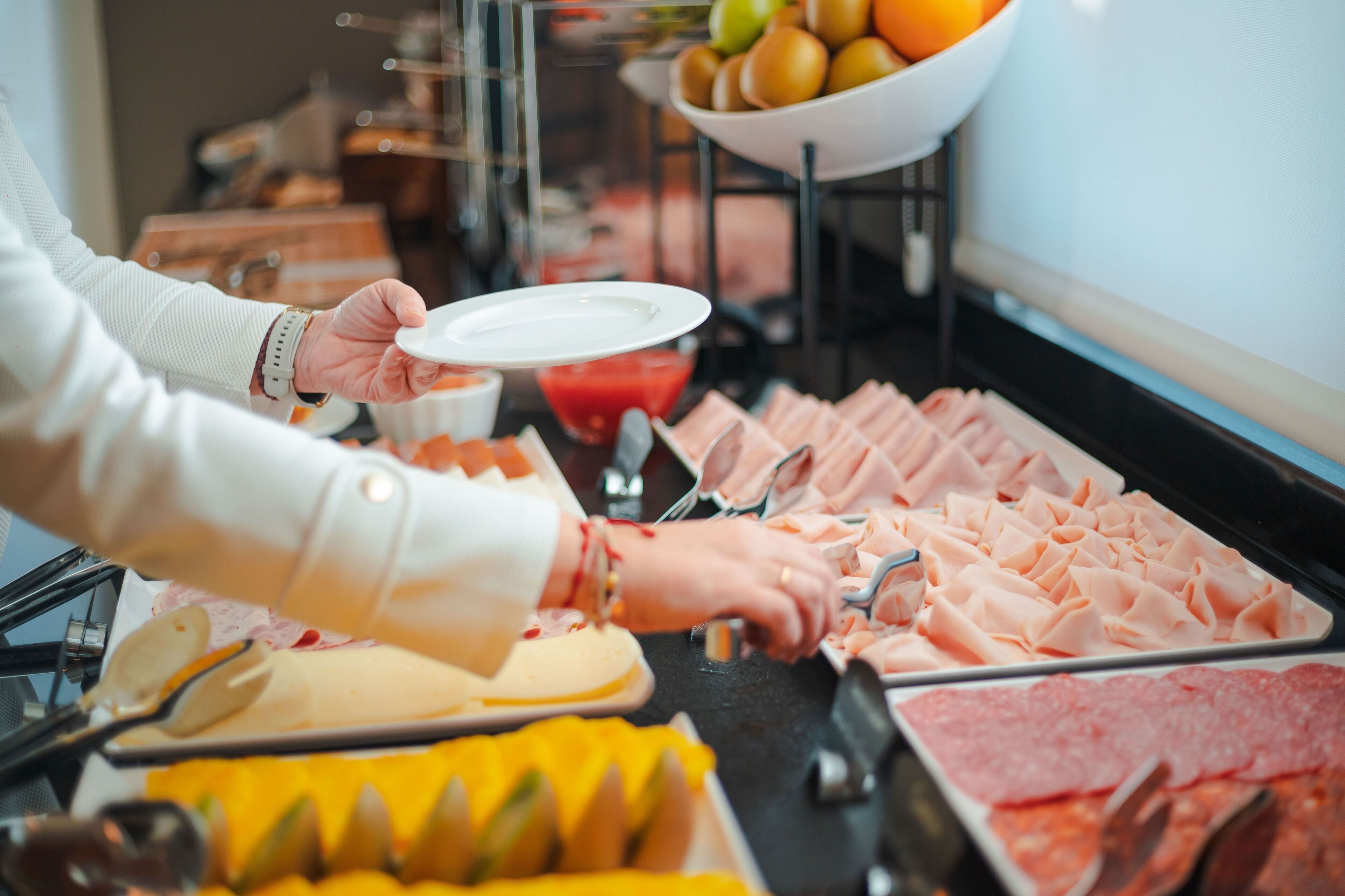A buffet with various food items including meats, cheeses, and fruits.