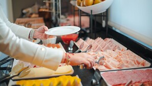 A buffet with various food items including meats, cheeses, and fruits.
