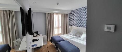 Una habitación de hotel moderna con una cama, un escritorio, una silla y un televisor.