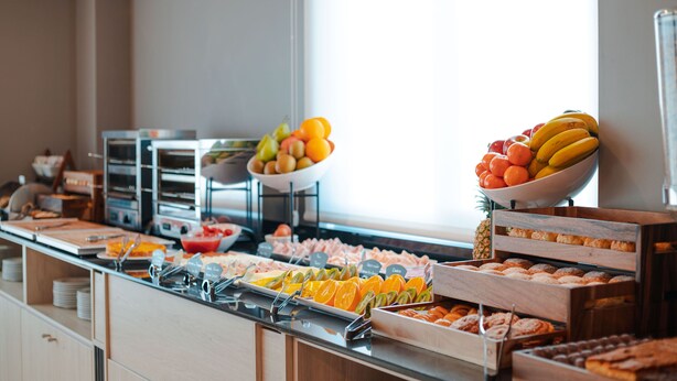 Un bufé con diversas opciones de comida, incluyendo frutas, pastelería y otros platos.