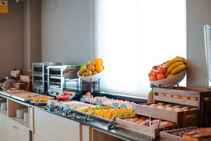 Un bufé con diversas opciones de comida, incluyendo frutas, pastelería y otros platos.