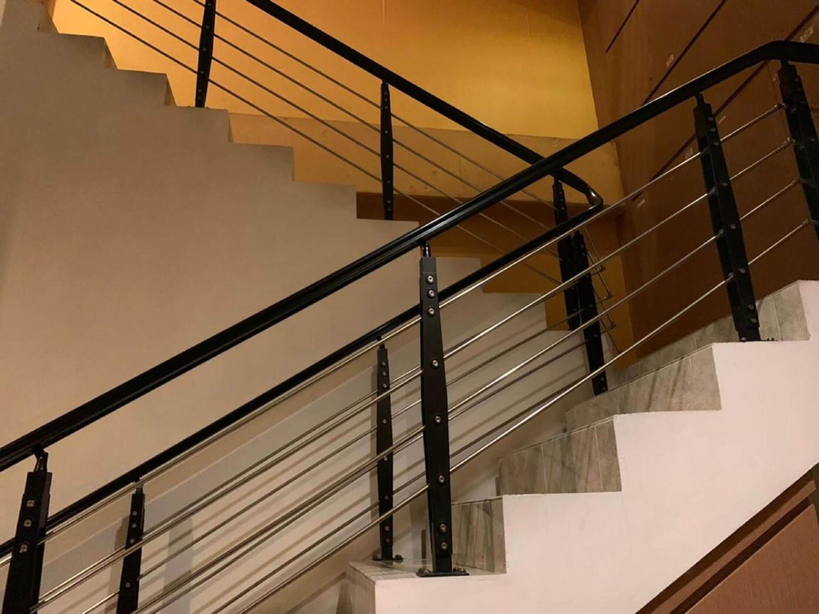 Una escalera con barandilla de metal negro y peldaños blancos.