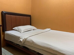 A single bed with a headboard, white bedding, and a wooden frame. - Rumah Shinta (Jakarta)