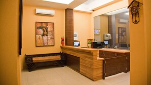 A reception area with a wooden reception desk, a bench, a clock, and artwork on the wall. - Rumah Shinta (Jakarta)