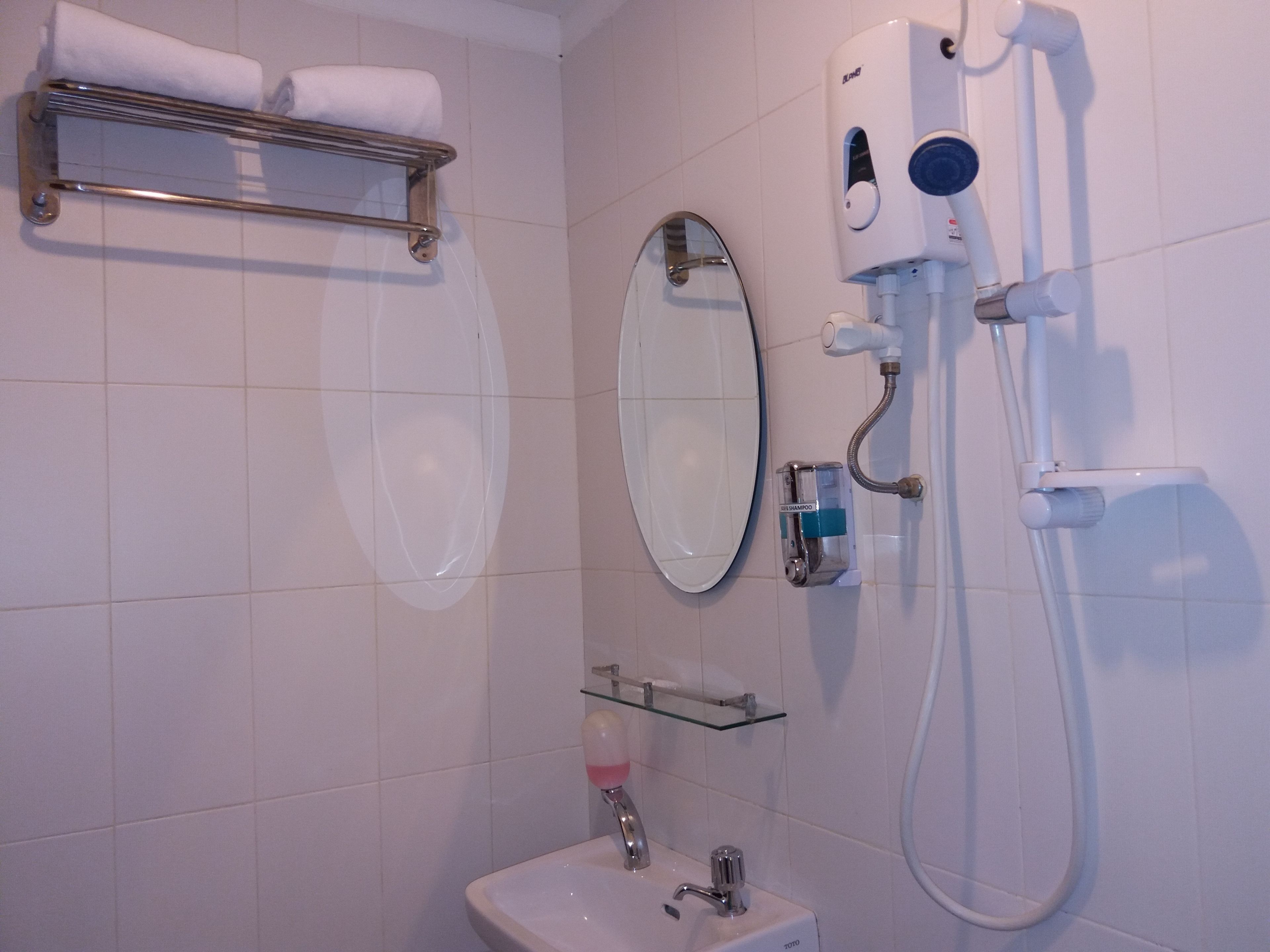A bathroom with a sink, mirror, towel rack, and a handheld showerhead.