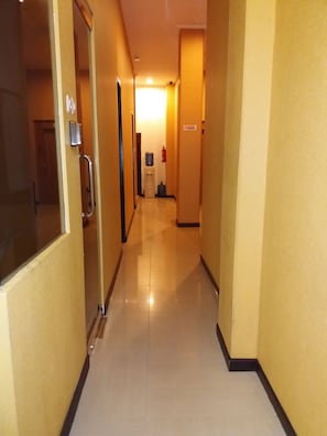 Stroll down this well-lit corridor, featuring a polished floor and a water dispenser for your convenience.