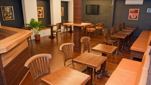 A restaurant with wooden tables and chairs, a potted plant, and artwork on the walls. - Rumah Shinta (Jakarta)