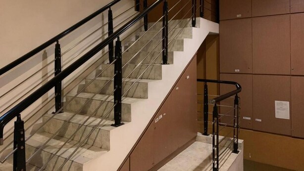 A staircase with a glass railing, beige steps, and brown walls. - Rumah Shinta (Jakarta)
